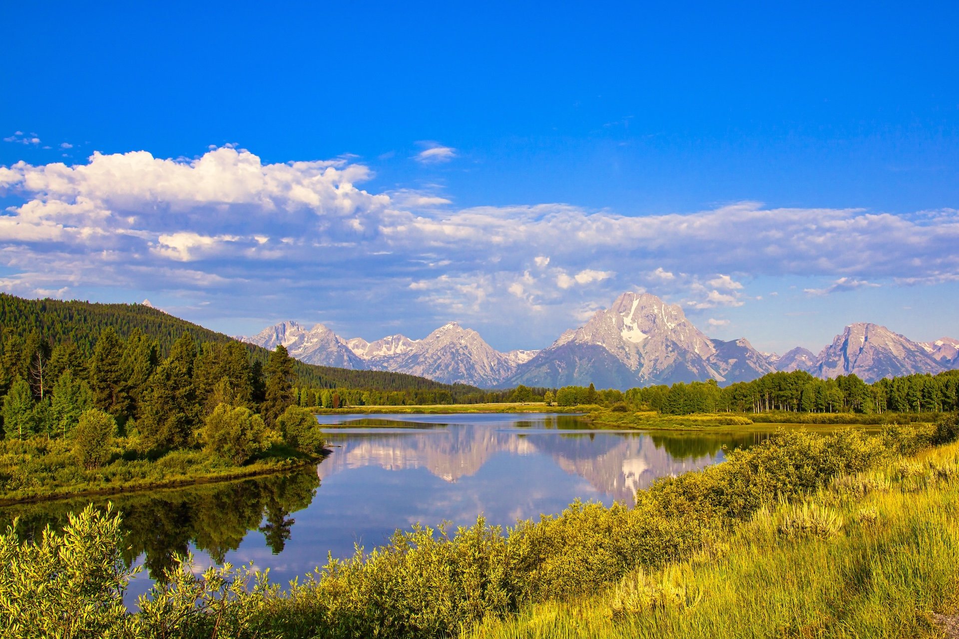 Mountain lake reflecting the Teton range under a bright summer sky